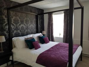1 dormitorio con cama con dosel y sábanas moradas en Ty Helyg Guest House, en Brecon