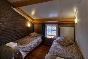 Cette chambre comprend 2 lits et un mur en briques. dans l'établissement Meschermolen 4, à Mesch