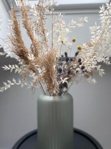 a white vase with dried plants in it on a table at Hotel Røde-Kro in Rødekro