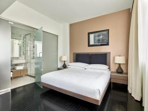 a bedroom with a large white bed and a bathroom at Smyth Tribeca in New York