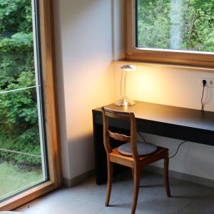 einen Schreibtisch mit einer Lampe und einem Stuhl neben einem Fenster in der Unterkunft Klemmbachidyll in Badenweiler