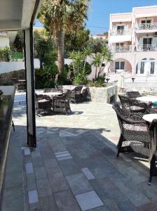 een terras met stoelen en tafels en een gebouw bij Villa Alexandra in Agia Marina Aegina