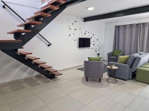 a living room with a staircase and a couch and a tv at Wilgespruit Manor Flat in Roodepoort