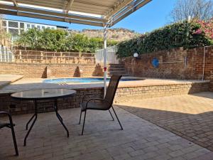 a patio with a table and chairs and an umbrella at Wilgespruit Manor Flat in Roodepoort