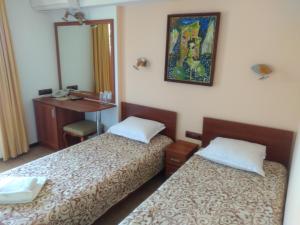 a room with two beds and a desk and a mirror at Panorama Family Hotel in Zlatograd