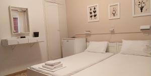 Habitación blanca con 2 camas y espejo. en Icarus Rooms, en Parikia