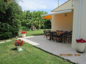 een patio met stoelen en een tafel met rode bloemen bij Locatlantique in Aytré