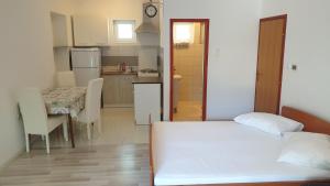 ein Schlafzimmer mit einem Bett und eine Küche mit einem Tisch in der Unterkunft Apartments Milka Pag in Pag