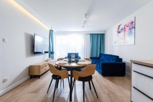 a living room with a table and chairs and a couch at Resort Apartamenty Klifowa Rewal 54 in Rewal