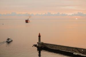 a lighthouse and a boat in a body of water at Hôtel Des Gouverneurs in Bastia
