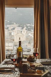 a table with a bottle of wine and two glasses at Hôtel Des Gouverneurs in Bastia