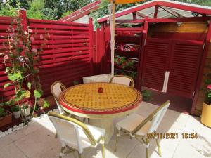 una mesa y sillas en un patio con una valla roja en Locatlantique, en Aytré