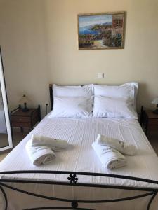 uma grande cama branca com duas almofadas em Villa Alexandra em Agia Marina Aegina