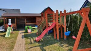 a playground in front of a log cabin at Willa Admiralska in Jarosławiec