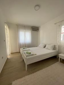 a white bedroom with a bed and a window at Luna Apartments in Budva