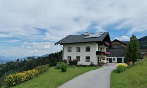 a white house with a black roof on a road at Maierlhof in Aich