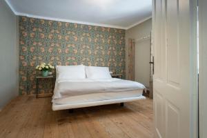 1 dormitorio con 1 cama y pared cubierta de papel pintado en Braumeisterhaus Schloss Eggenberg, en Eggenberg
