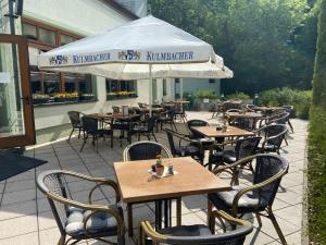 ein Restaurant im Freien mit Tischen, Stühlen und einem Sonnenschirm in der Unterkunft Jembo Park Hotel in Jena