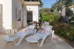 3 weiße Stühle und ein Tisch auf der Terrasse in der Unterkunft Villa Pointe Alègre in Grimaud