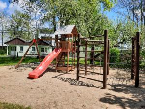 a playground with a red slide in the sand at Jembo Park Hotel in Jena