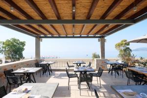 an outdoor patio with tables and chairs and a view of the ocean at Margo Beach Hotel in Gythio