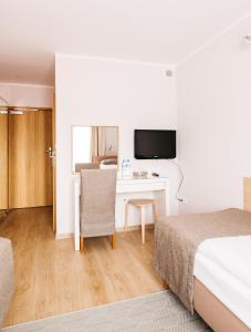 a hotel room with a bed and a desk with a tv at Hotel Chata Za Wsią in Mysłakowice