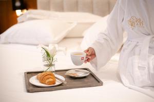 a tray with a cup of coffee and croissants on a bed at Hotel Sokrati in Tirana