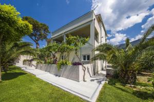 a white house with a fence and palm trees at Villa Dvori Viškovi in Podstrana