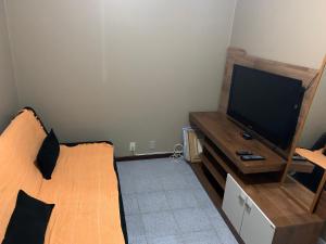 1 dormitorio con 1 cama y TV de pantalla plana en Apartamento em Cabo Frio, en Cabo Frío