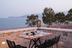 a table and chairs on a wall with the ocean at Margo Beach Hotel in Gythio