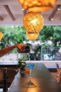 a person pouring a drink into a glass on a bar at Margo Beach Hotel in Gythio