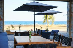 a table with chairs and umbrellas on the beach at Margo Beach Hotel in Gythio