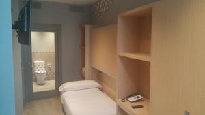 um pequeno quarto com uma cama e um espelho em Hotel Atalaia B&B em Santiago de Compostela