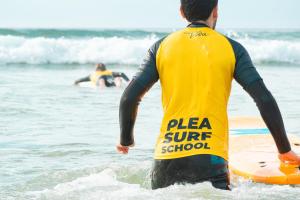 un homme debout dans l'océan avec une planche de surf dans l'établissement Plea Beach House, à Loredo