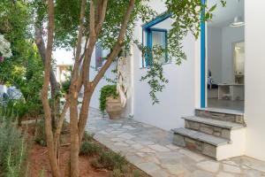 a white house with a blue window and stairs at Blue Moon Apartments in Makry Gialos