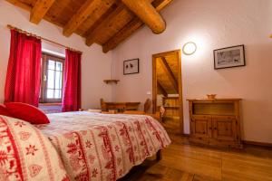 a bedroom with a bed with red curtains and a television at Lou Tsantelet in Cogne