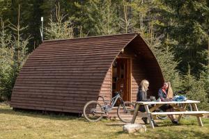 people sitting on a bench in a wooded area at Badaguish forest lodges, eco camping pods and tent camping in Aviemore