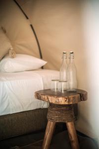 duas garrafas de vidro numa mesa de madeira ao lado de uma cama em Uman Glamping & Cenote Tulum em Tulum