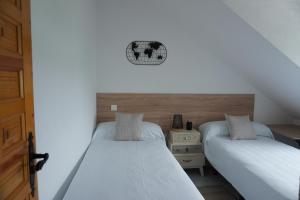 sypialnia z 2 łóżkami i zegarem na ścianie w obiekcie Hostal La Biela 43 w mieście Galizano
