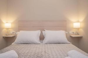 a bed with two white pillows and two lamps at El sueño de Zante City Center Apartments in Zakynthos Town