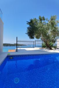 a blue swimming pool with a tree in the background at Villa Gloria in Cavtat