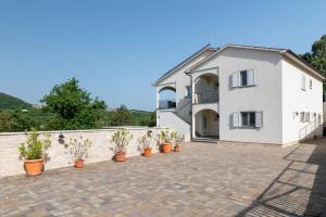 a white house with potted plants on a patio at Villa Vires in Labin