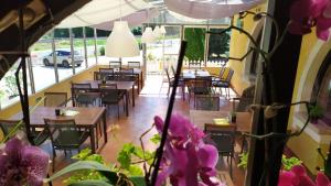 a restaurant with tables and chairs and purple flowers at Arcadia Guesthouse in Ábrahámhegy