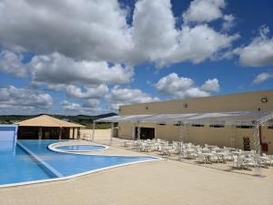 a resort with a swimming pool and white chairs at Lacazzona Hotel in Belo Jardim