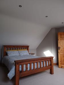 a bedroom with a wooden bed with a wooden bench at AshBurnum Cottage in Bandon