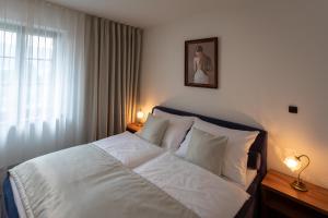 um quarto com uma cama com lençóis brancos e uma janela em Hotel Zámeček Pod Hradem Starý Jičín 111 em Starý Jičín