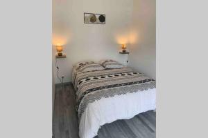 1 cama en una habitación con 2 lámparas en la pared en Maison solognote proche Chambord, en Saint Laurent Nouan