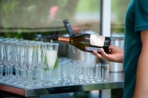 a person pouring a bottle of wine into wine glasses at Hotel "VITAMIN" in Krasnodar