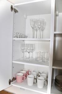 um armário cheio de copos e copos de vinho em Tani Nocleg Ełk - Apartament I love Ełk em Ełk