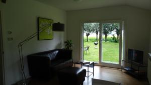 a living room with a leather couch and a sliding glass door at Apartment ARDA in Spijk